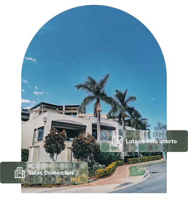 Fachada de empreendimento com salas comerciais e loteamento aberto, rodeada por palmeiras em um dia de céu azul